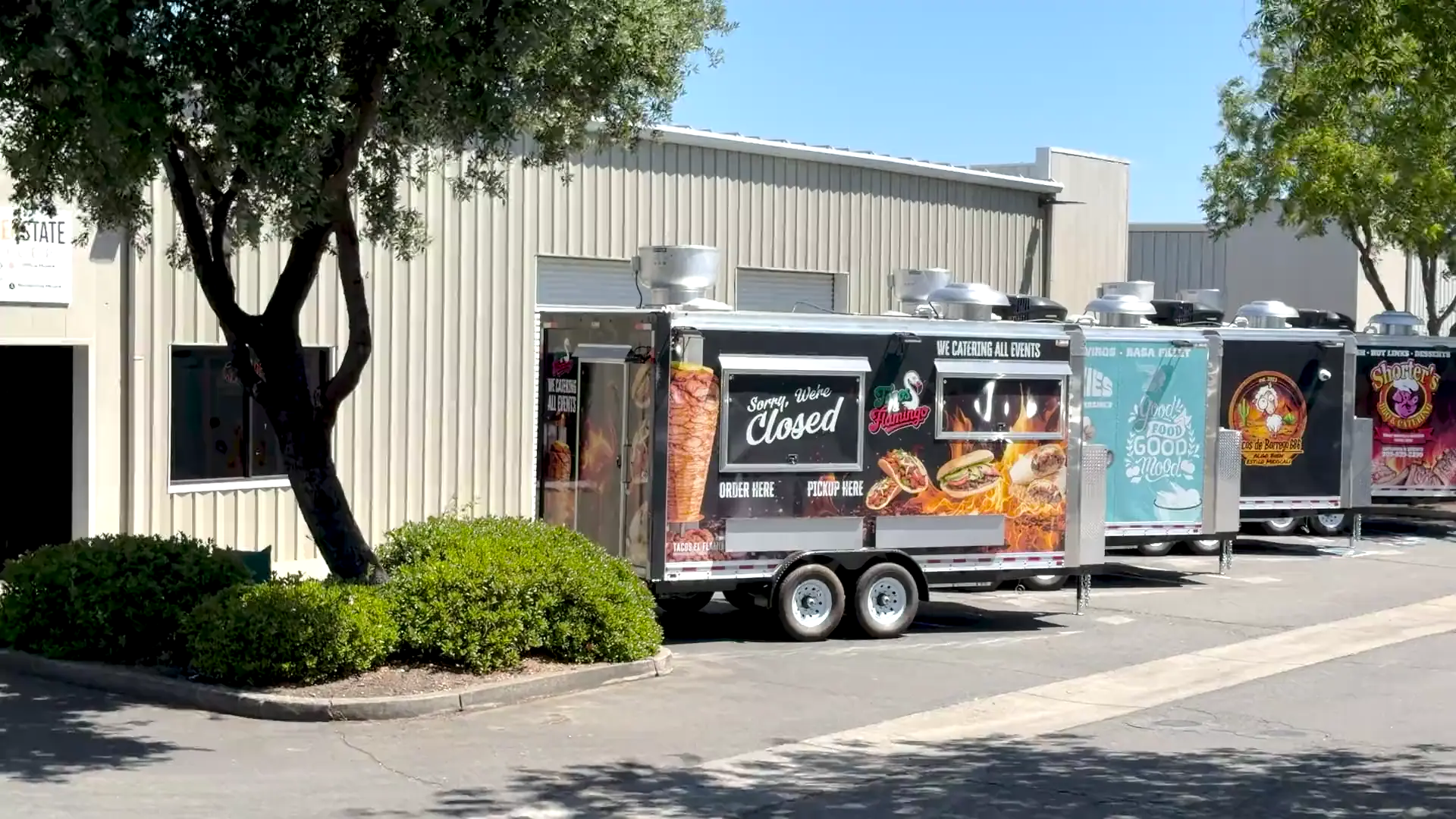 Custom food trailers with full-color wraps lined up outside the Golden State Trailers factory in Olivehurst, California, then a walk through the stainless steel commercial kitchen inside one