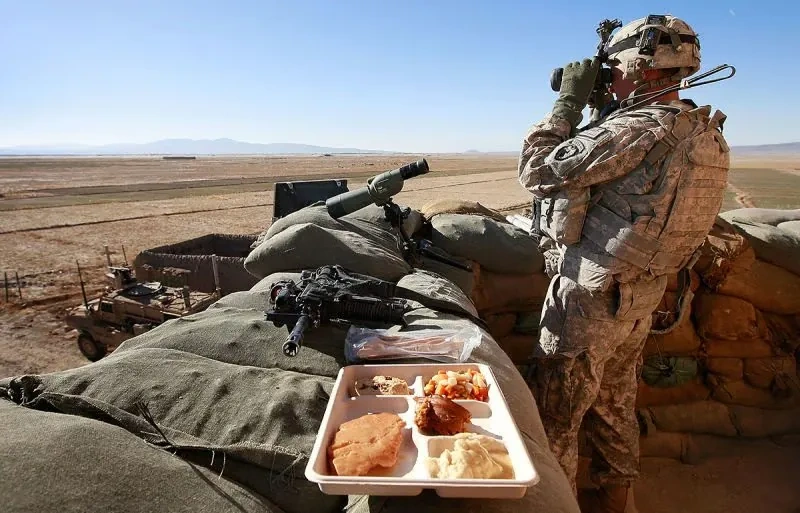 Soldier with a meal tray at a field outpost — point-of-need feeding