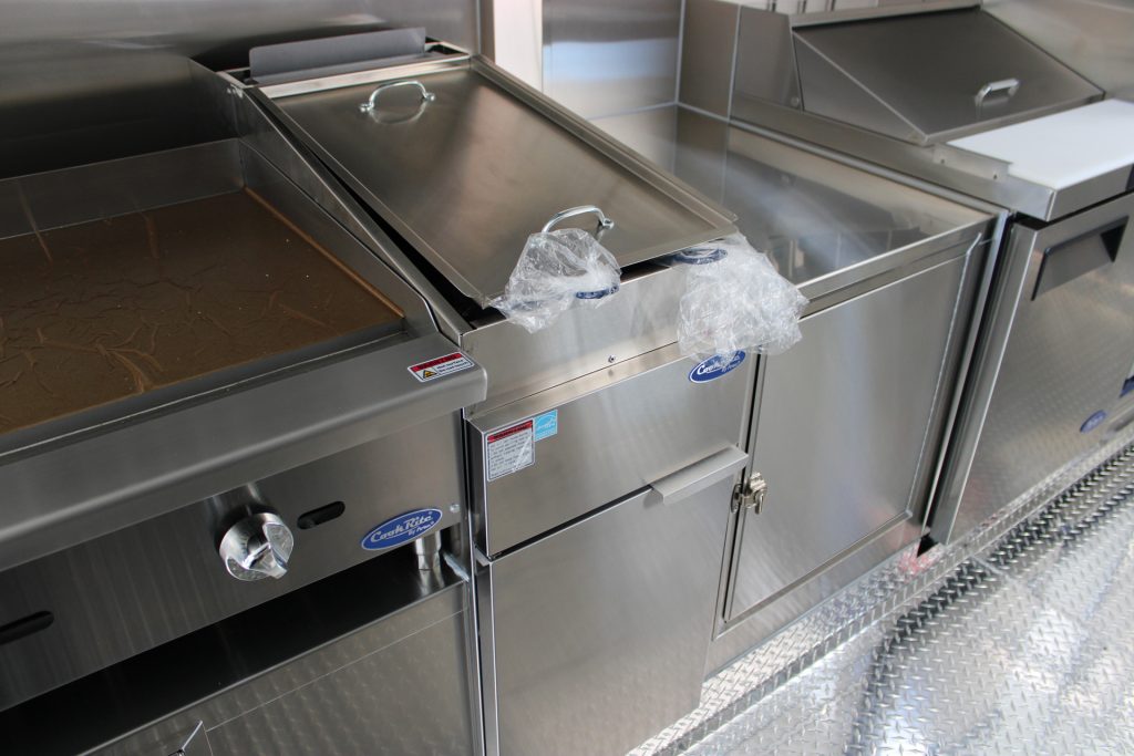 Commercial cooking equipment and stainless steel work surface inside school food trailer
