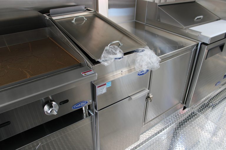 Commercial cooking equipment and stainless steel work surface inside school food trailer