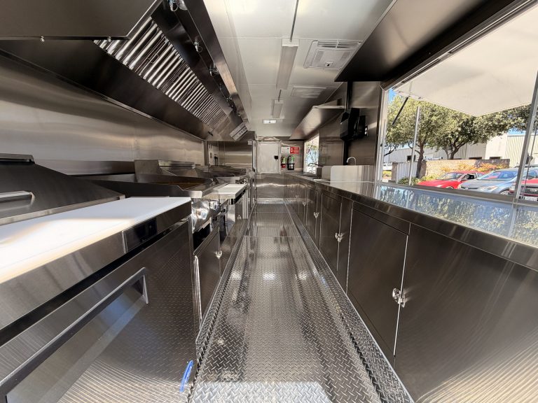 Interior of The Salty Buccaneer 22-ft school food trailer with commercial cooking line and central aisle