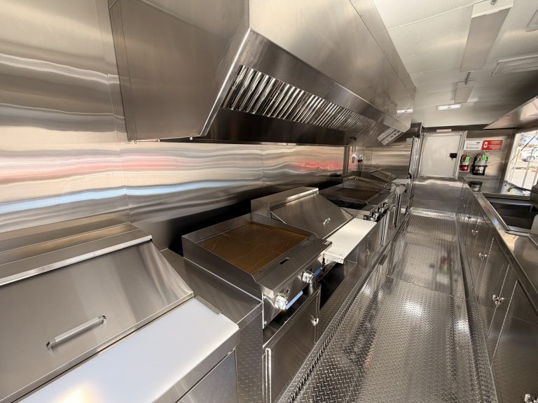Commercial cooking equipment beneath ventilation hood in The Salty Buccaneer school food trailer