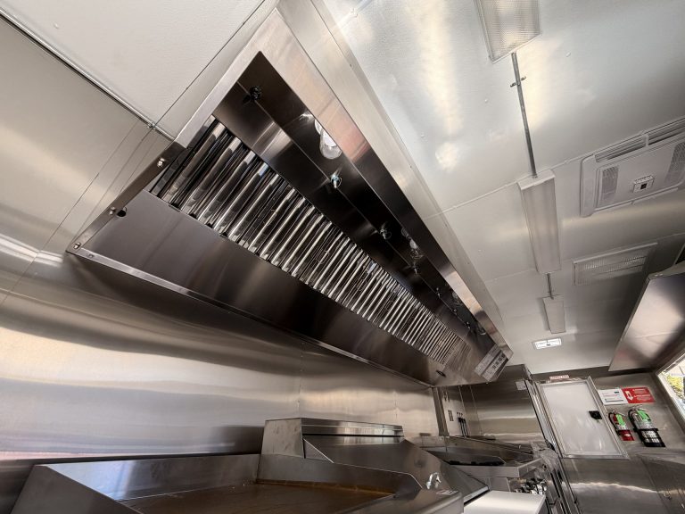 Stainless steel kitchen hood above cooking line inside custom school food trailer