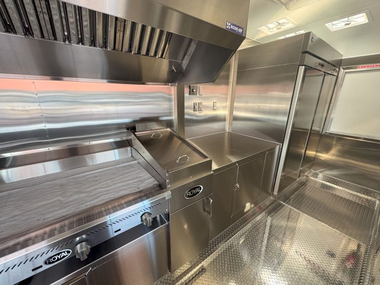 Commercial cooking line beneath ventilation hood inside Cougar’s Grill school food trailer