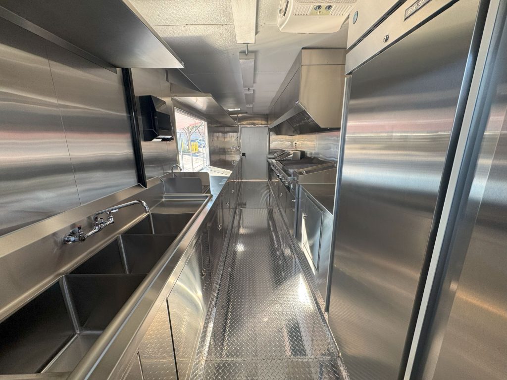 Interior of Cougar’s Grill school food trailer with stainless steel kitchen and central aisle