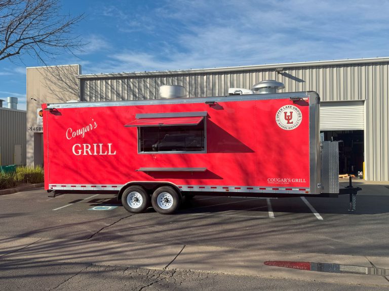 Side view of Cougar’s Grill 24-ft school food trailer with red school branding and concession window