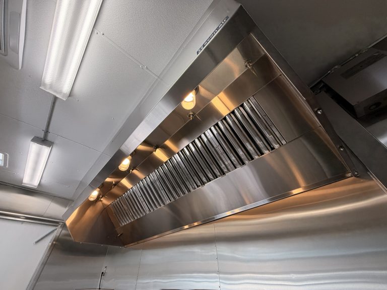 Commercial grade stainless steel exhaust hood ventilation system inside a food trailer with UL 710 compliant hood, UL-classified baffle grease filters, built-in lighting, and des.
