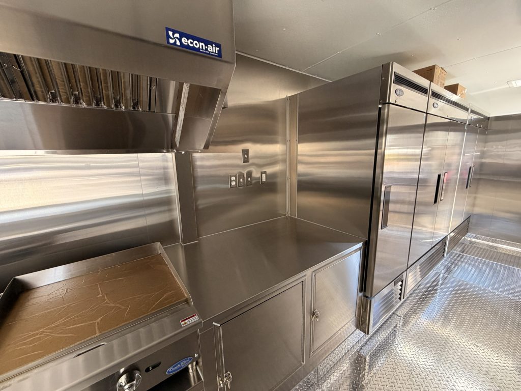 custom pizza food trailer interior with reach-in refrigerators, freezer, stainless steel work surface, and commercial cold storage
