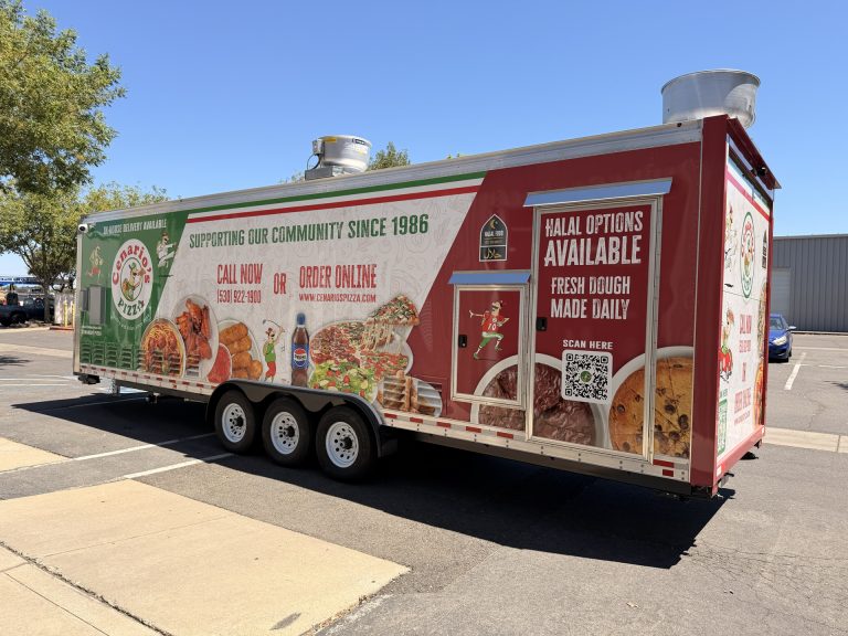 custom pizza trailer rear-side exterior with branded wrap, entry door, rooftop ventilation, and triple-axle chassis