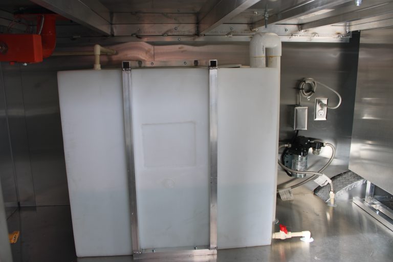 Fresh water tank system inside food trailer with commercial water pump, plumbing connections, and food-grade potable water storage tank