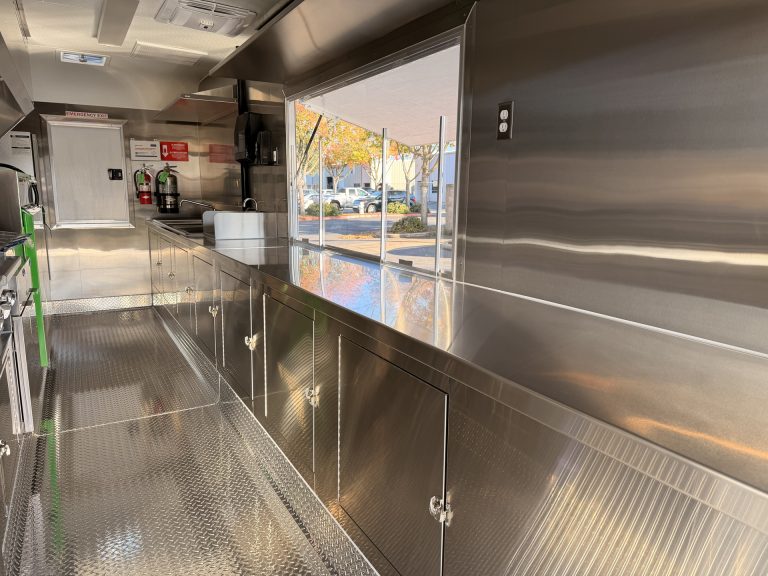 Long stainless steel prep counter inside BBQ food trailer in Gonzales CA with serving window