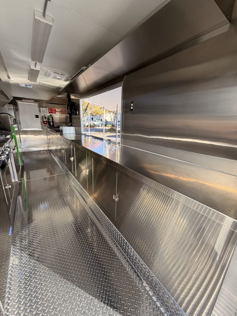 Service side interior of BBQ food trailer in Gonzales CA with stainless steel walls and cabinets