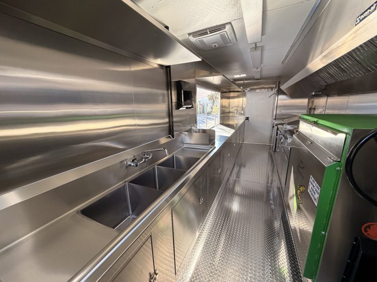 Triple sink and prep area inside BBQ food trailer in Gonzales CA with stainless steel finish