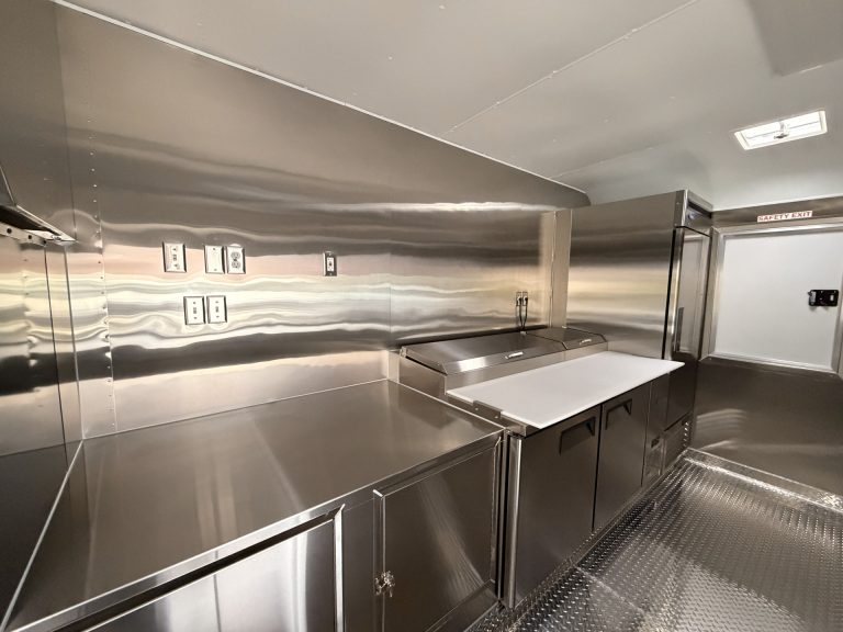 Stainless steel prep counter and refrigerated pizza table inside food trailer