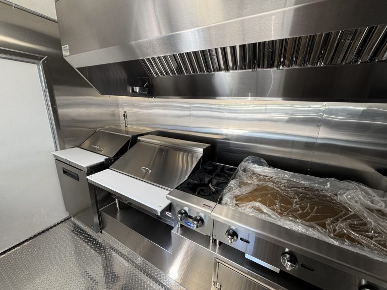 Griddle and range under ventilation hood inside 16ft taco food trailer in Watsonville CA