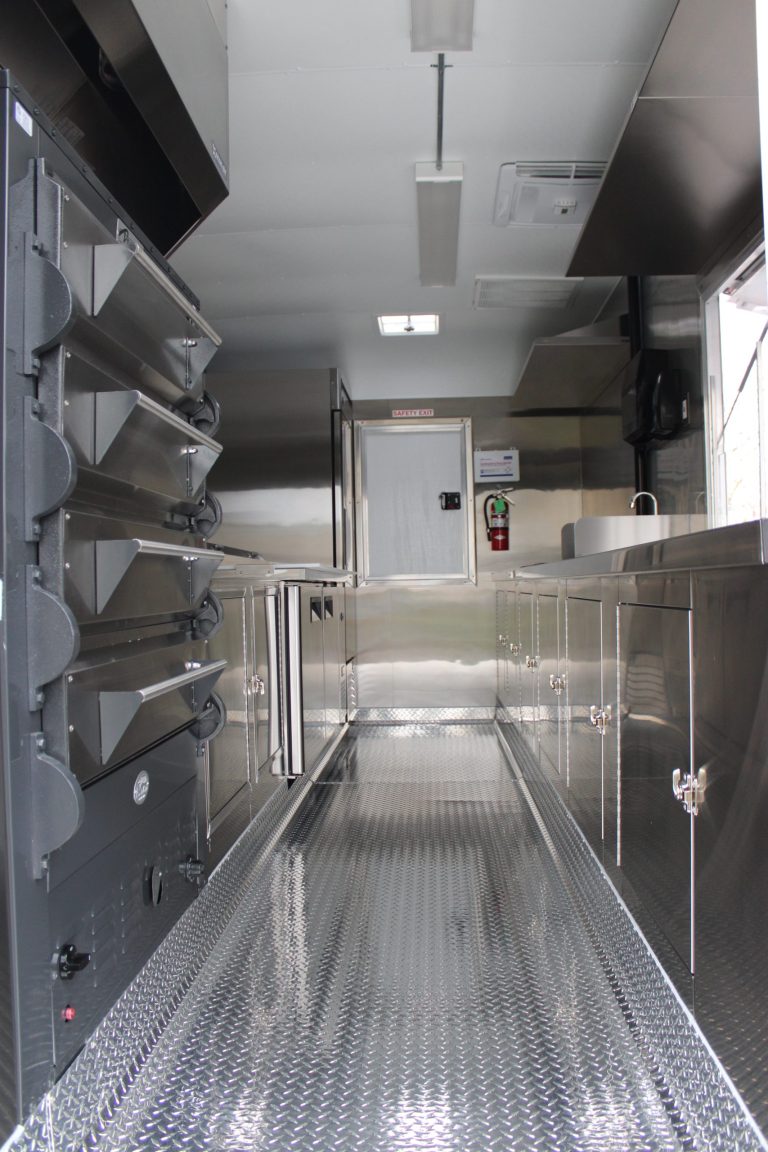 Full interior aisle of pizza food trailer with ovens and stainless cabinets