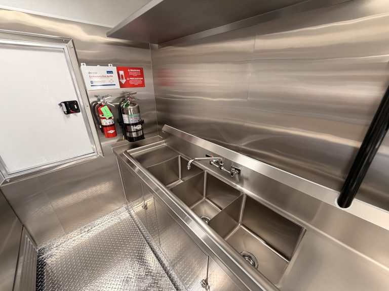 Smashed Broz Burgers food trailer three-compartment sink with hand wash sink, fire extinguisher mount and stainless steel splash guard, health department compliant build
