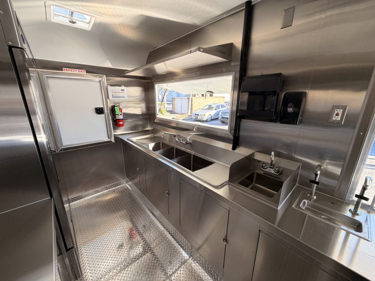 Sip'n on Sunshine lemonade trailer rear zone with three-compartment sink, hand wash sink, microwave, welded stainless steel cabinets and rear entry door