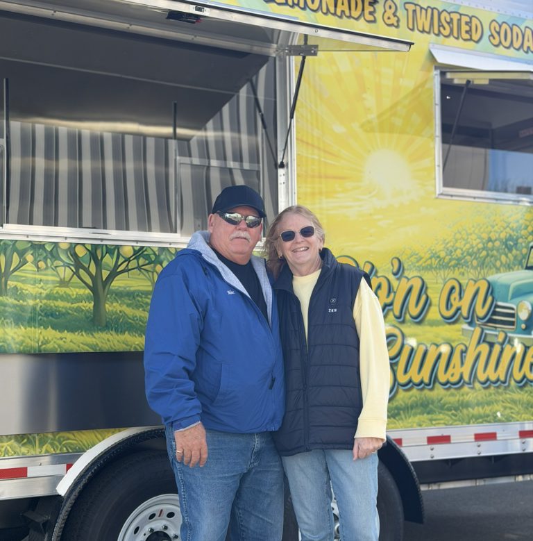 Sip'n on Sunshine food trailer owners standing in front of their custom 16ft lemonade trailer with lemon orchard 3M wrap, Golden State Trailers delivery day