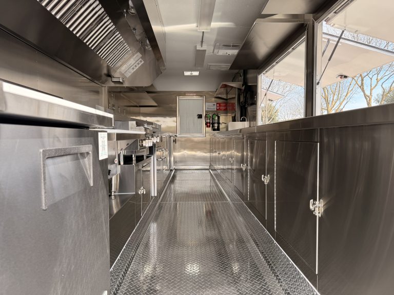 End Zone Kitchen food trailer full interior length view with exhaust hood, stainless steel prep counters, welded cabinets and diamond plate flooring, commercial kitchen build