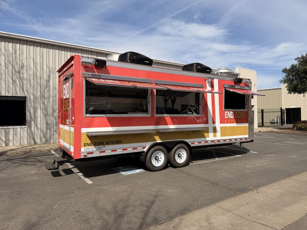End Zone Kitchen custom 22ft American food trailer full side view with red and gold 3M wrap, dual serving windows and rooftop exhaust units, Santa Clara CA