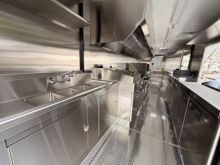 Mya's Teriyaki food trailer interior with custom welded stainless steel cabinets, commercial sink, hood ventilation system and diamond plate flooring