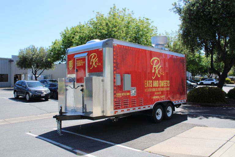 Driver side view of 18ft kettle corn concession trailer with red custom wrap and aluminum front storage