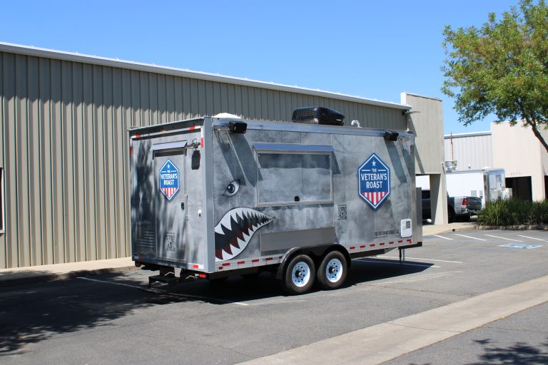 Rear side view of 18ft American food trailer with military graphics and tandem axle setup