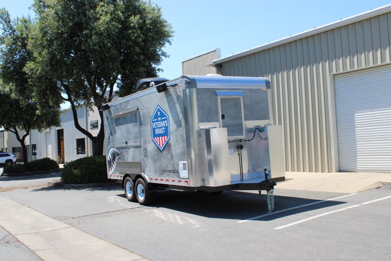 Front side angle of 18ft American food trailer with polished aluminum front and military graphics