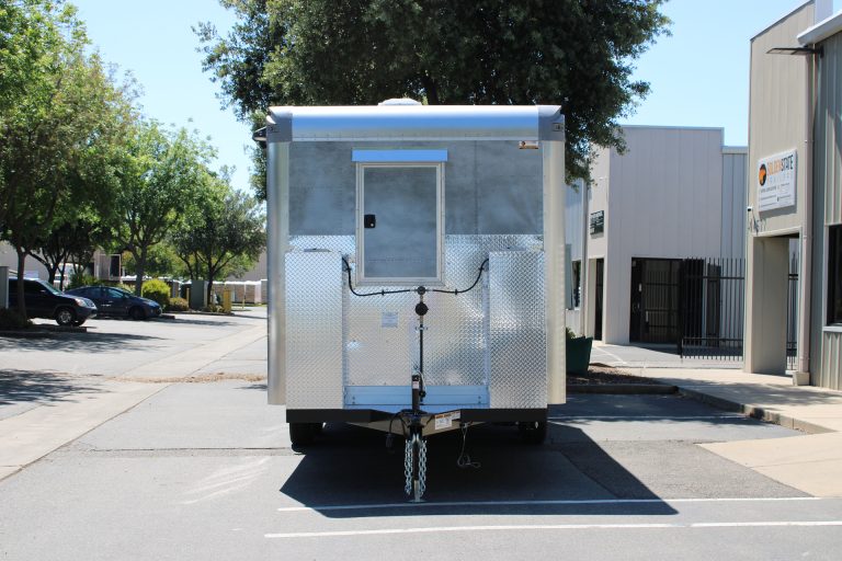 Front exterior of 18ft American food trailer with polished aluminum storage and tandem axle chassis