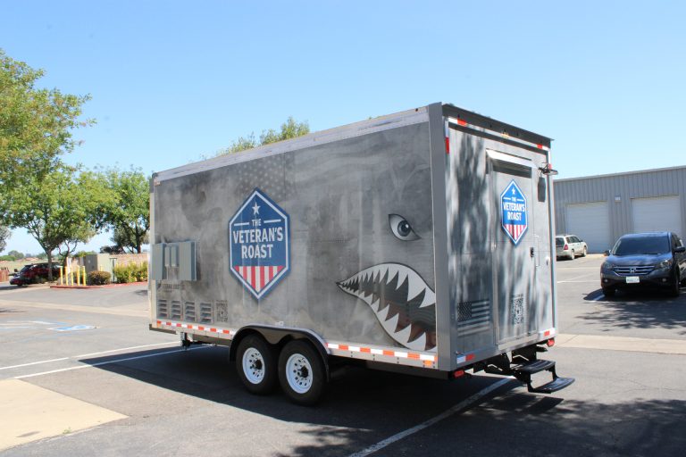Rear driver side angle of 18ft American food trailer with military wrap and tandem axle setup