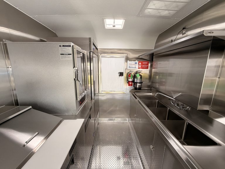 Food trailer full interior rear view with three compartment sink fire extinguisher stainless steel fit-out and diamond plate flooring