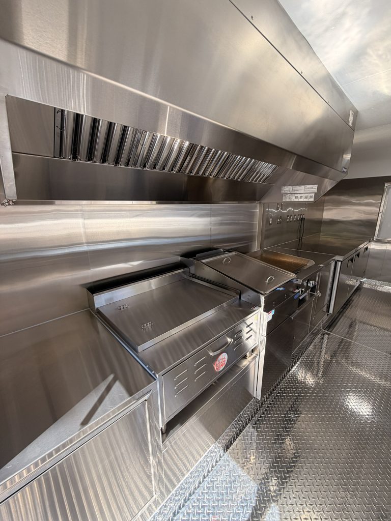 Commercial cooking equipment and exhaust hood inside 18ft kettle corn food trailer kitchen