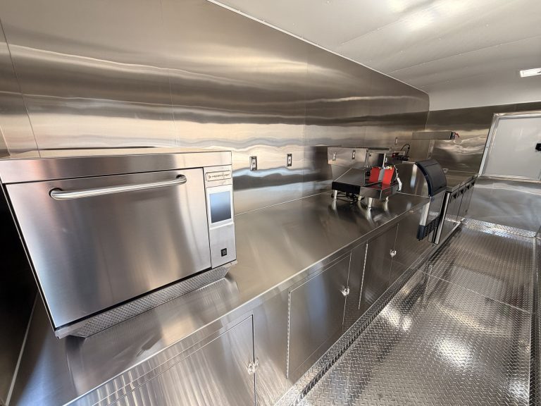 Stainless steel prep counter and storage cabinets inside 18ft American food trailer kitchen