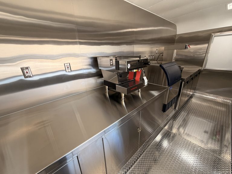Stainless steel prep station and commercial equipment inside 18ft American food trailer kitchen