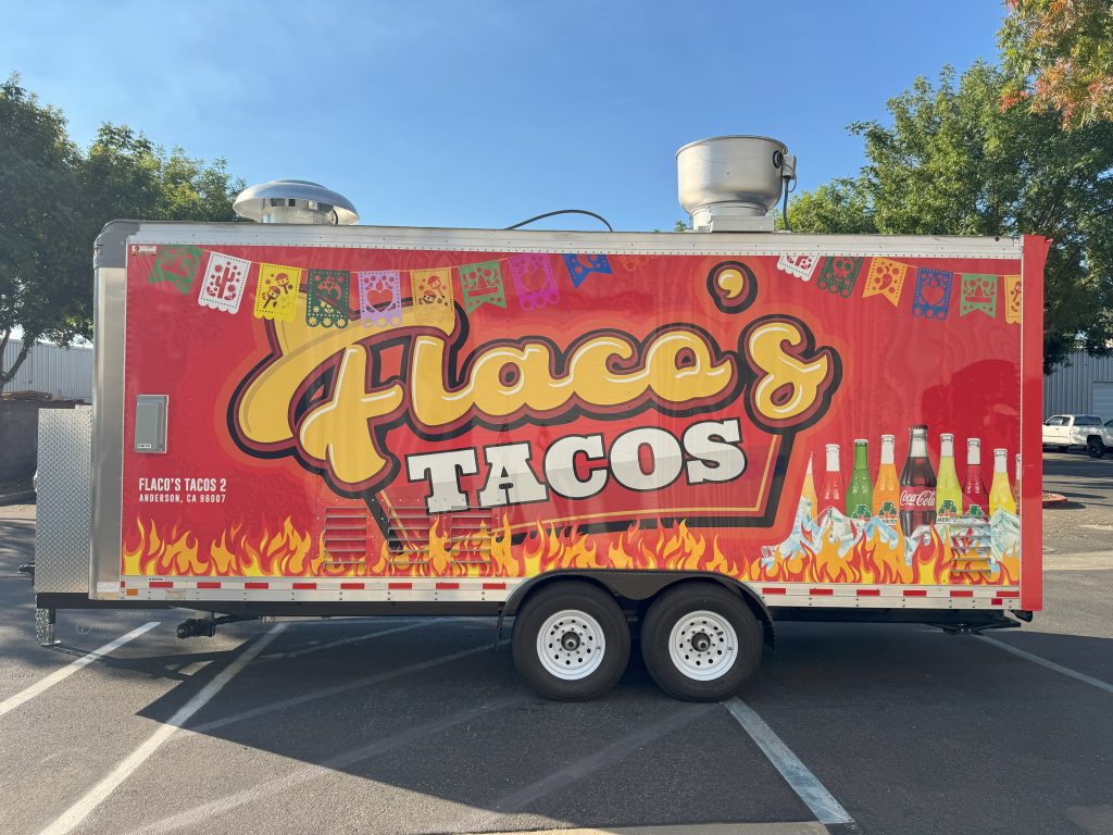 Red “Flaco’s Tacos” trailer with flame graphics and papel picado