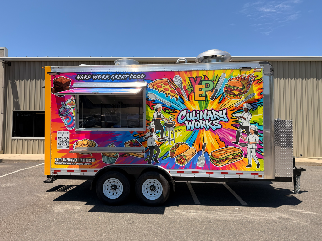 Custom food trailer with colorful graphic wrap and side serving window