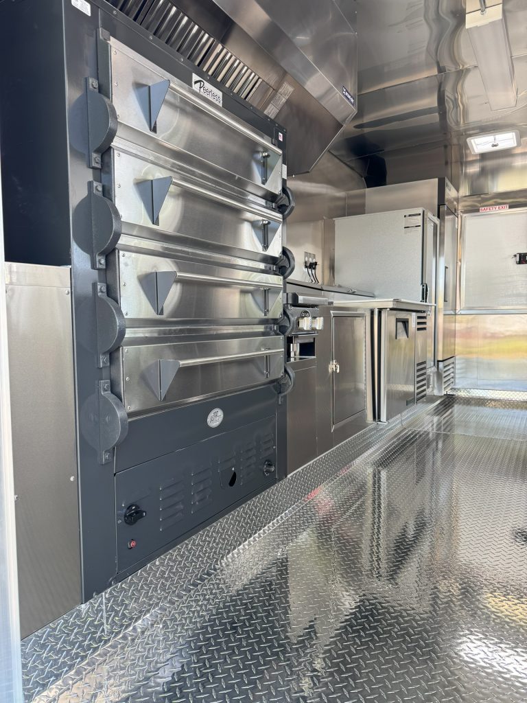 Commercial pizza ovens and stainless steel kitchen inside 16ft golf course food trailer
