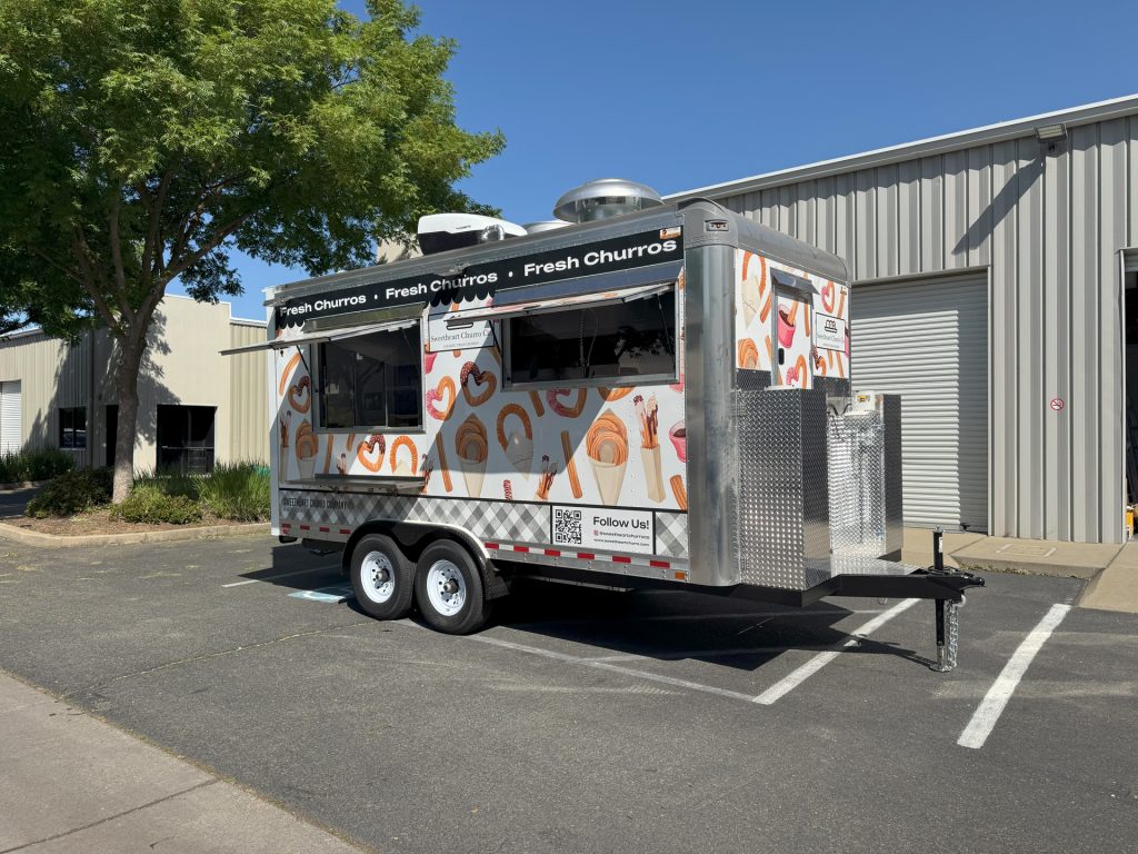 16ft churro food trailer passenger side three-quarter view white wrap churro illustrations open service windows - Sweetheart Churro Co Minden NV Golden State Trailers