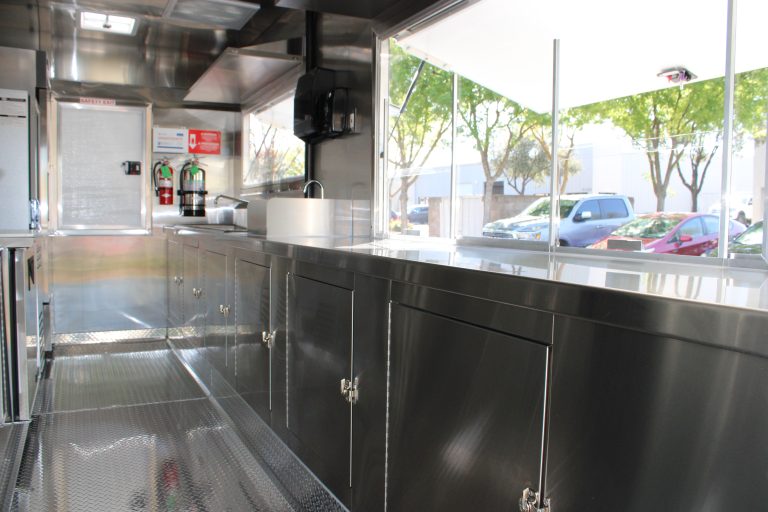 Commercial pizza oven and stainless steel prep area inside 16ft golf course food trailer