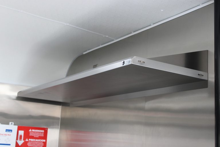 Stainless steel wall-mounted shelf inside the Avenal High School school food trailer