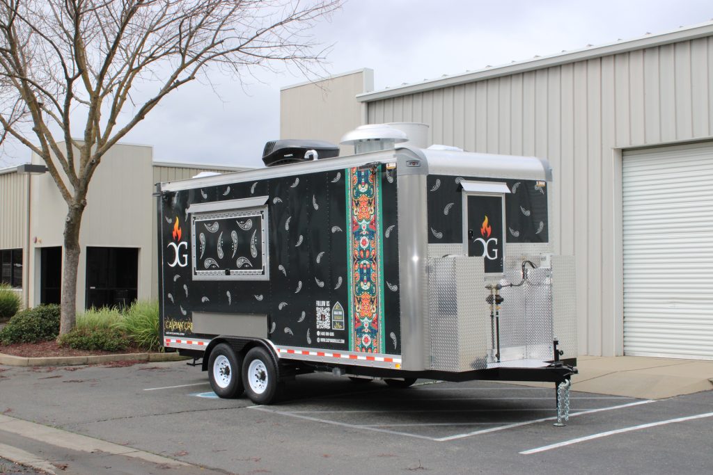 Black and silver food trailer with green graphics, serving window, and tandem axles.