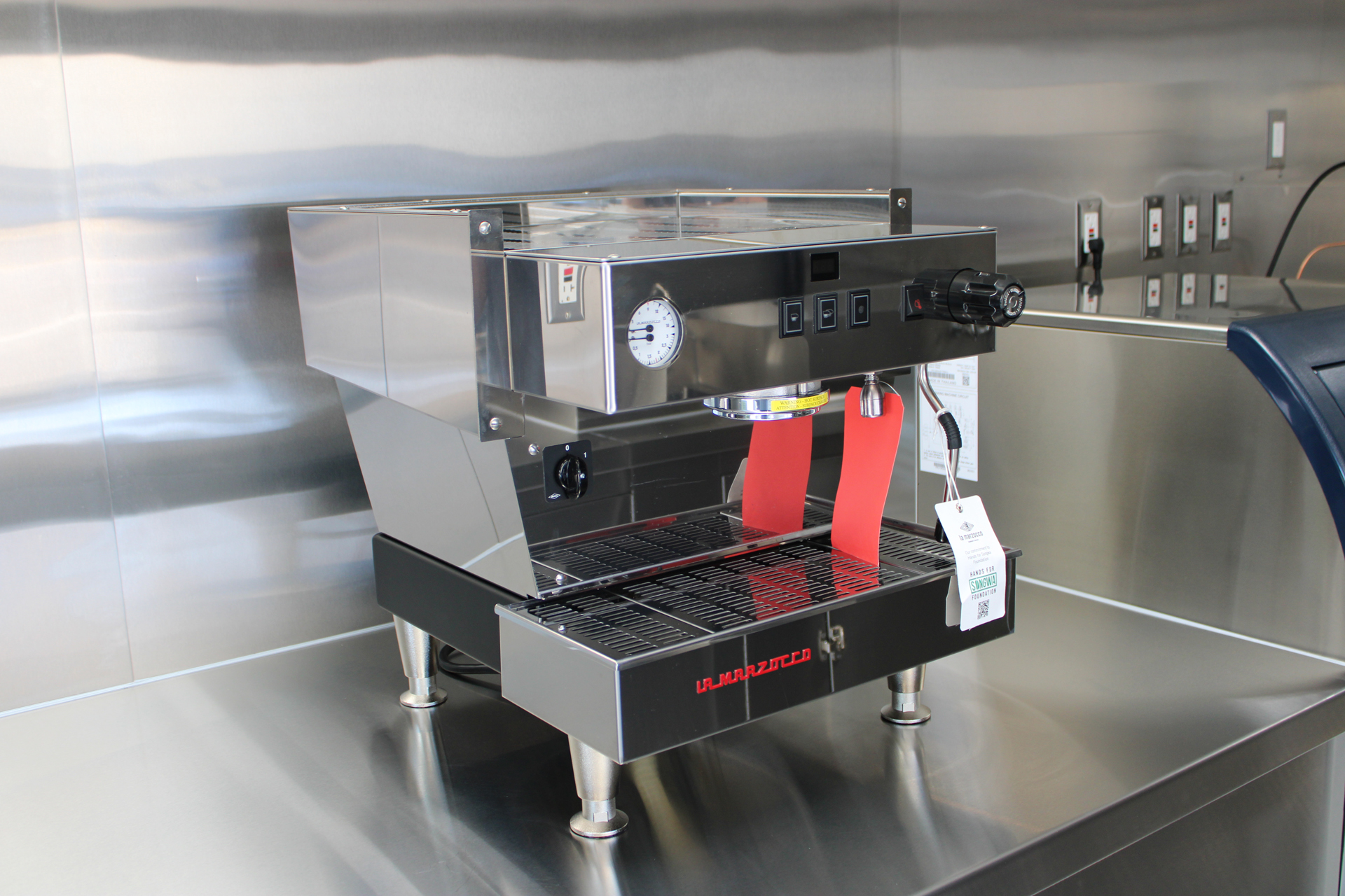 La Marzocco espresso machine installed on a stainless steel counter inside a coffee trailer