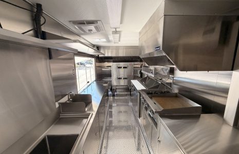 Custom food trailer interior with stainless steel sinks, commercial cooking equipment, and ventilation system.