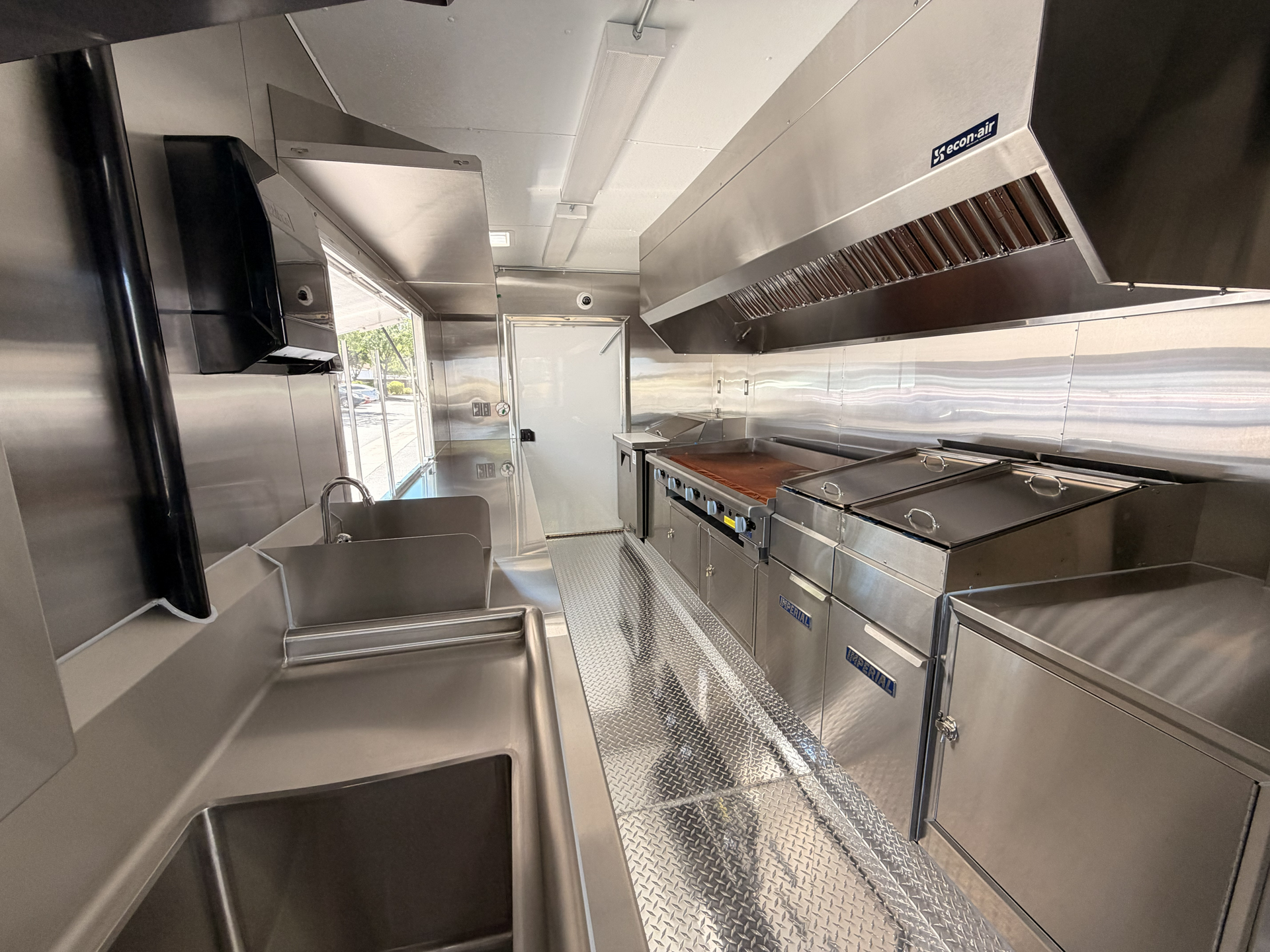 Interior of an 18-foot burger food trailer with a commercial griddle, deep fryers, sinks, and exhaust hood.