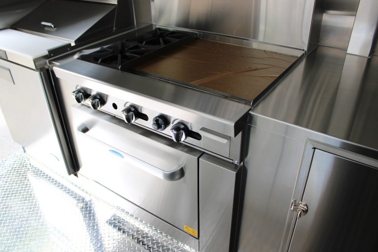 Commercial combination gas range with stainless steel workspace inside the custom 16ft coffee food trailer.