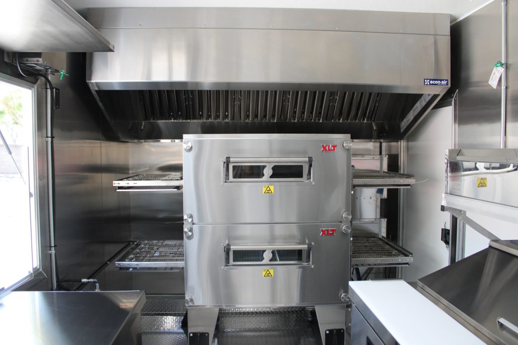 Double-stack conveyor oven inside a custom pizza food trailer.
