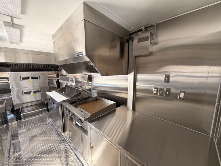 custom pizza trailer interior with stainless steel counters, commercial cooking line, ventilation hood, and organized workspace