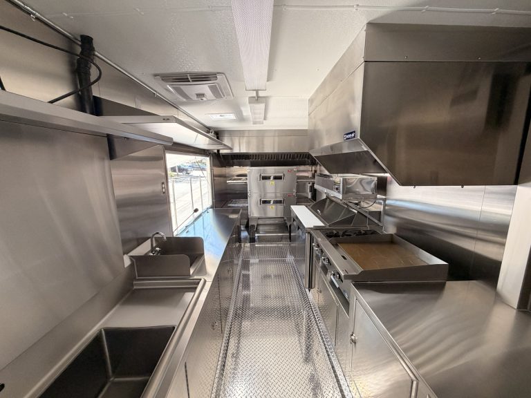 commercial pizza food trailer interior with stainless steel work surfaces, ventilation hood, and prep area