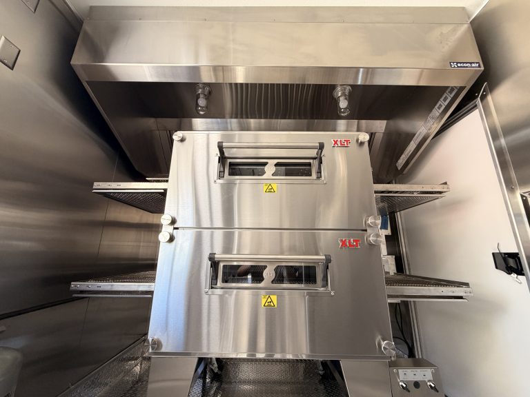 commercial conveyor pizza oven with dedicated hood inside a custom mobile pizza kitchen